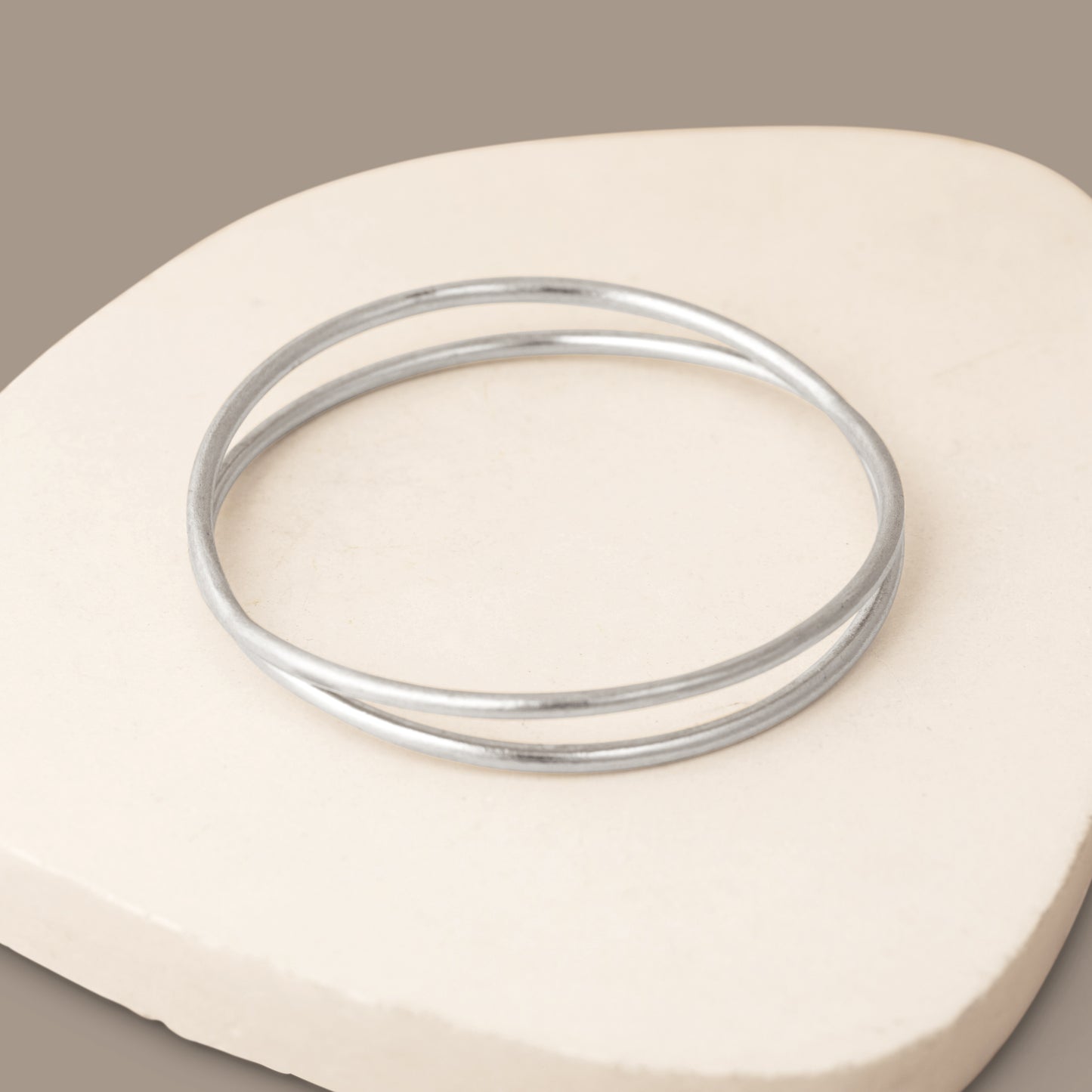 Close up of a silver bangle bracelet on a white stone background