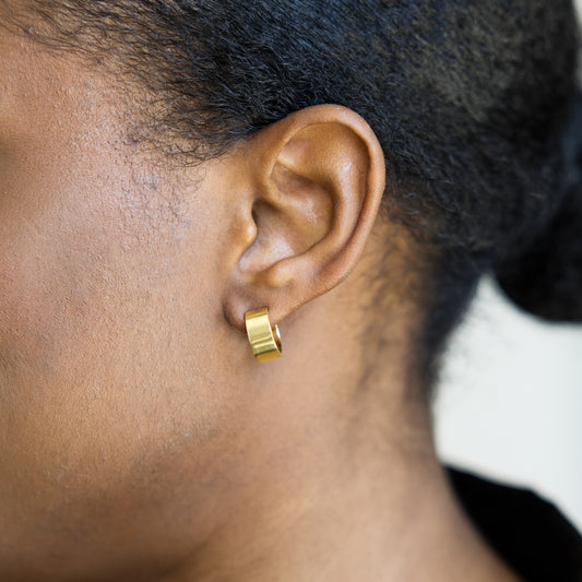 Close-up of an ear wearing a gold hoop earring
