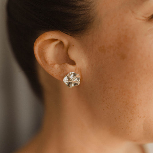 Close up of a person wearing a silver floral earring