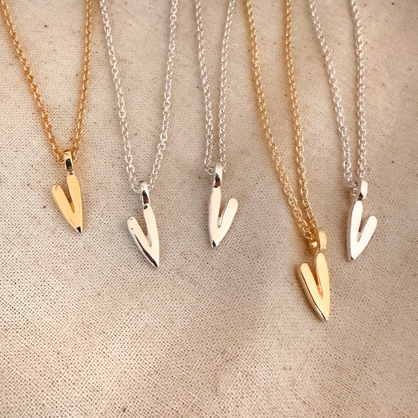 5 gold and silver heart necklaces on fabric background