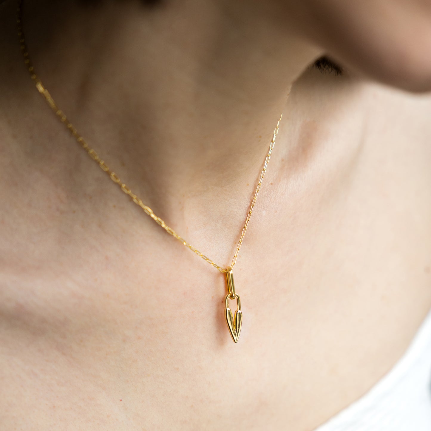 Gold necklace with a heart pendant on a person's neck