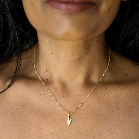 Gold necklace with a heart pendant worn by a person