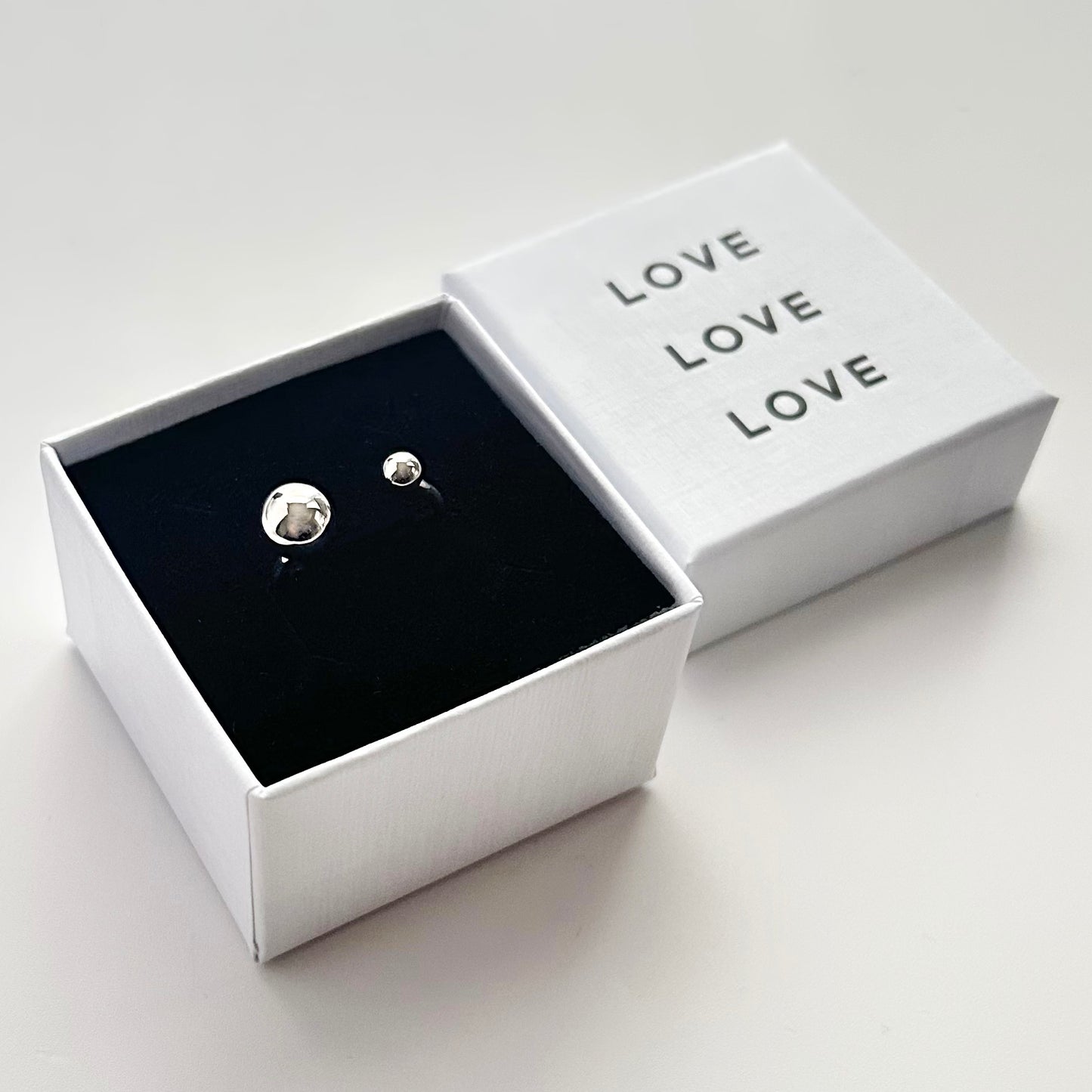 Silver orb ring in a white box with 'LOVE' text on a light gray background