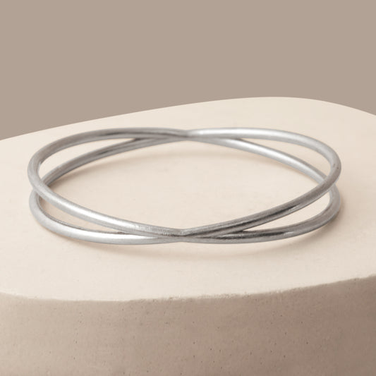 Close up of a silver bangle bracelet on a white stone background