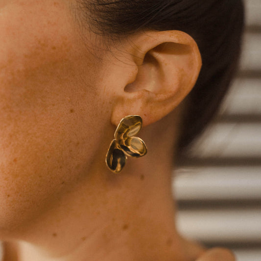 Close up of a person wearing a gold plant earring