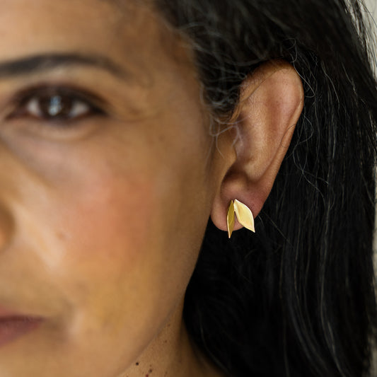 Close-up of a woman wearing a gold leaf-shaped earring.