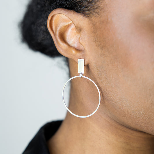 Close-up of a person wearing a silver hoop earring