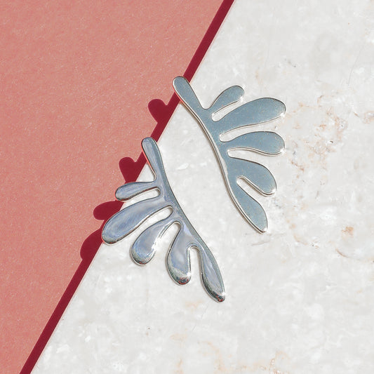 A pair of silver leaf-shaped earrings against a white background