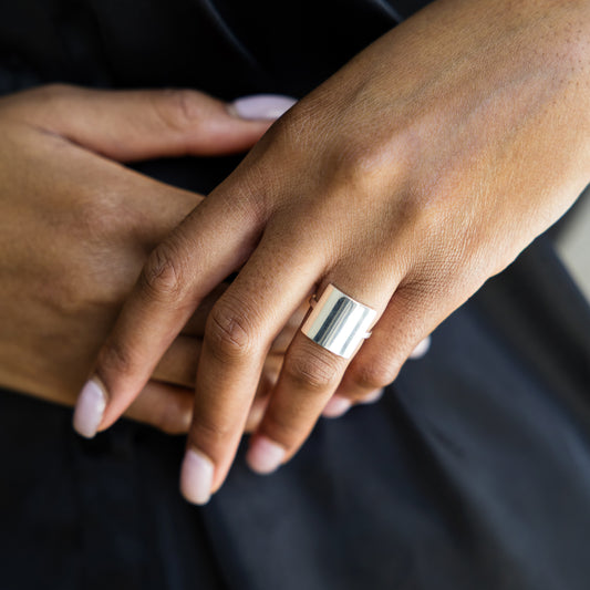 Close-up of hands with a silver ring on a dark background