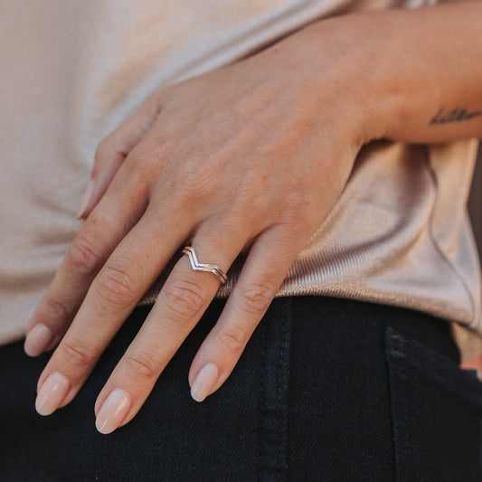 Close up of a hand wearing stacking pointed silver rings