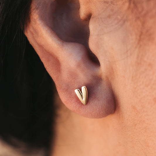 Close up of a person wearing a heart-shaped stud earring