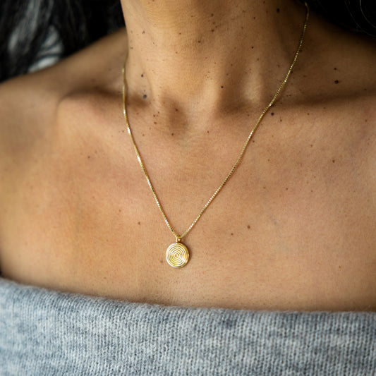 Gold necklace with a circular pendant on a person's neck