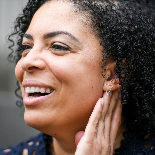 Person wearing triangle-shaped silver earrings.