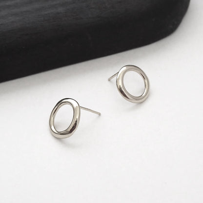 Silver circular earrings on a white surface with a black background