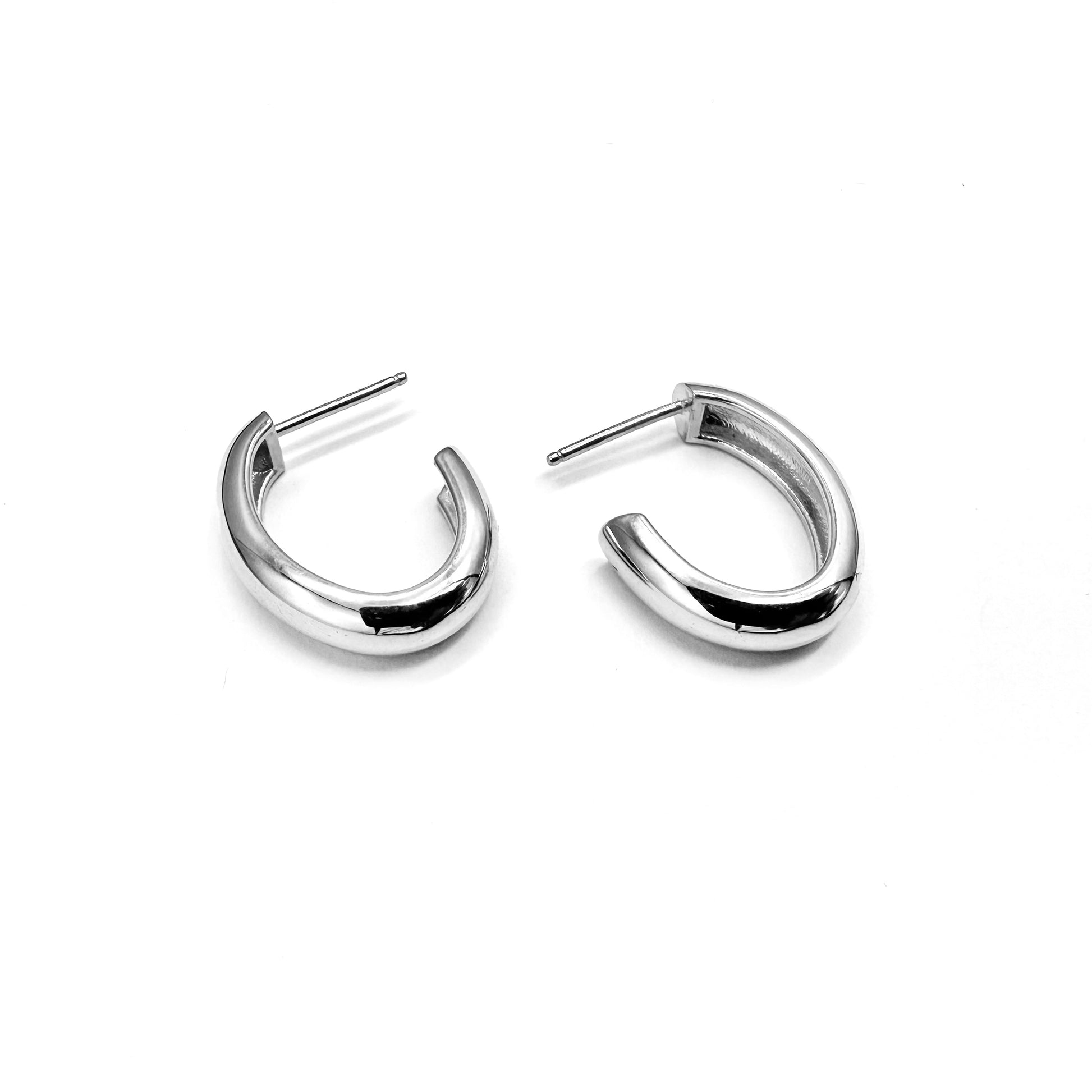 A pair of silver oval hoop earrings on a white background