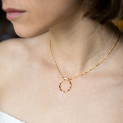 Gold necklace with a circular pendant on a person's neck