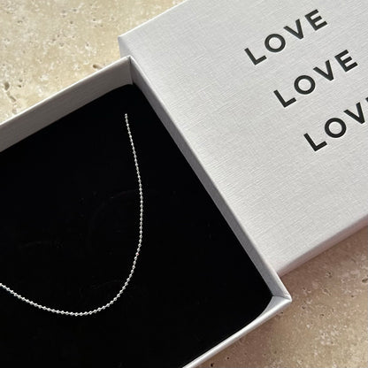 Silver necklace in a box with 'LOVE' text