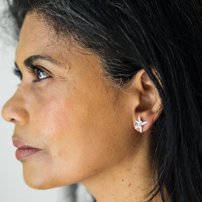 Close-up of a woman wearing a star-shaped earring with a neutral background