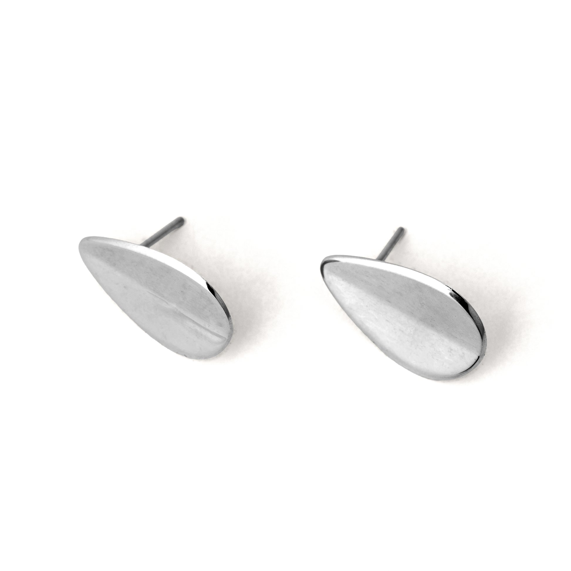 A pair of silver-colored teardrop-shaped earrings with a folded concavity design, displayed against a white background.