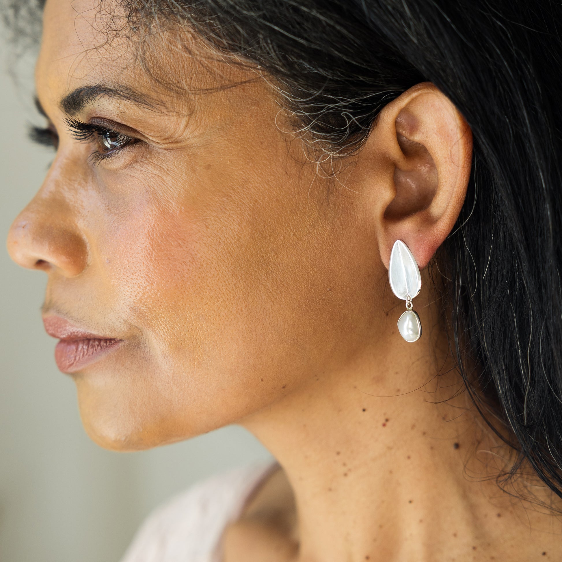 Close-up of a woman wearing a teardrop-shaped earring with a blurred background
