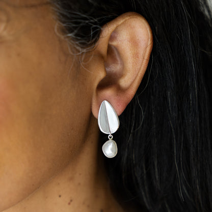 Silver earring with a pearl drop worn by a person
