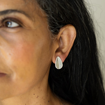 Close-up of a woman wearing a silver teardrop earring.