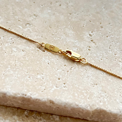 Gold necklace box chain on a textured beige surface