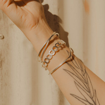 Close up of a person wearing three silver bangle bracelets