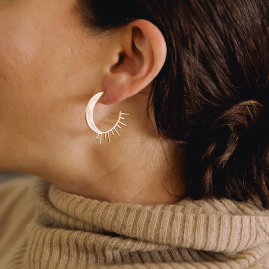 Close up of a person wearing a sun and moon hoop earring