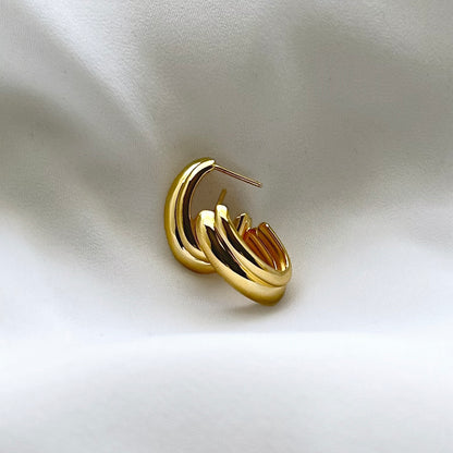 Gold hoop earring on a light fabric background