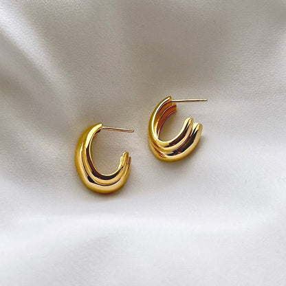Gold hoop earrings on a light fabric background