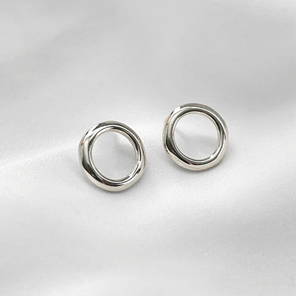 Pair of silver circular earrings on a light gray background