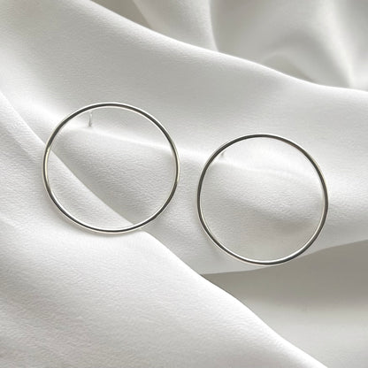 Pair of silver hoop earrings on a white fabric background