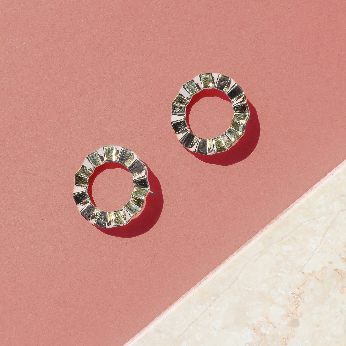 A pair of modern geometric earrings with a faceted, circular design