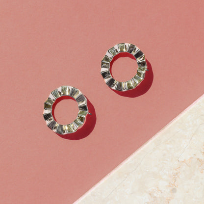 A pair of modern geometric earrings with a faceted, circular design