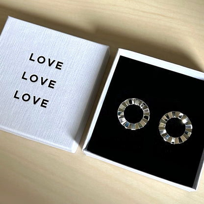 Silver hoop earrings in a box with 'LOVE' text on a wooden surface