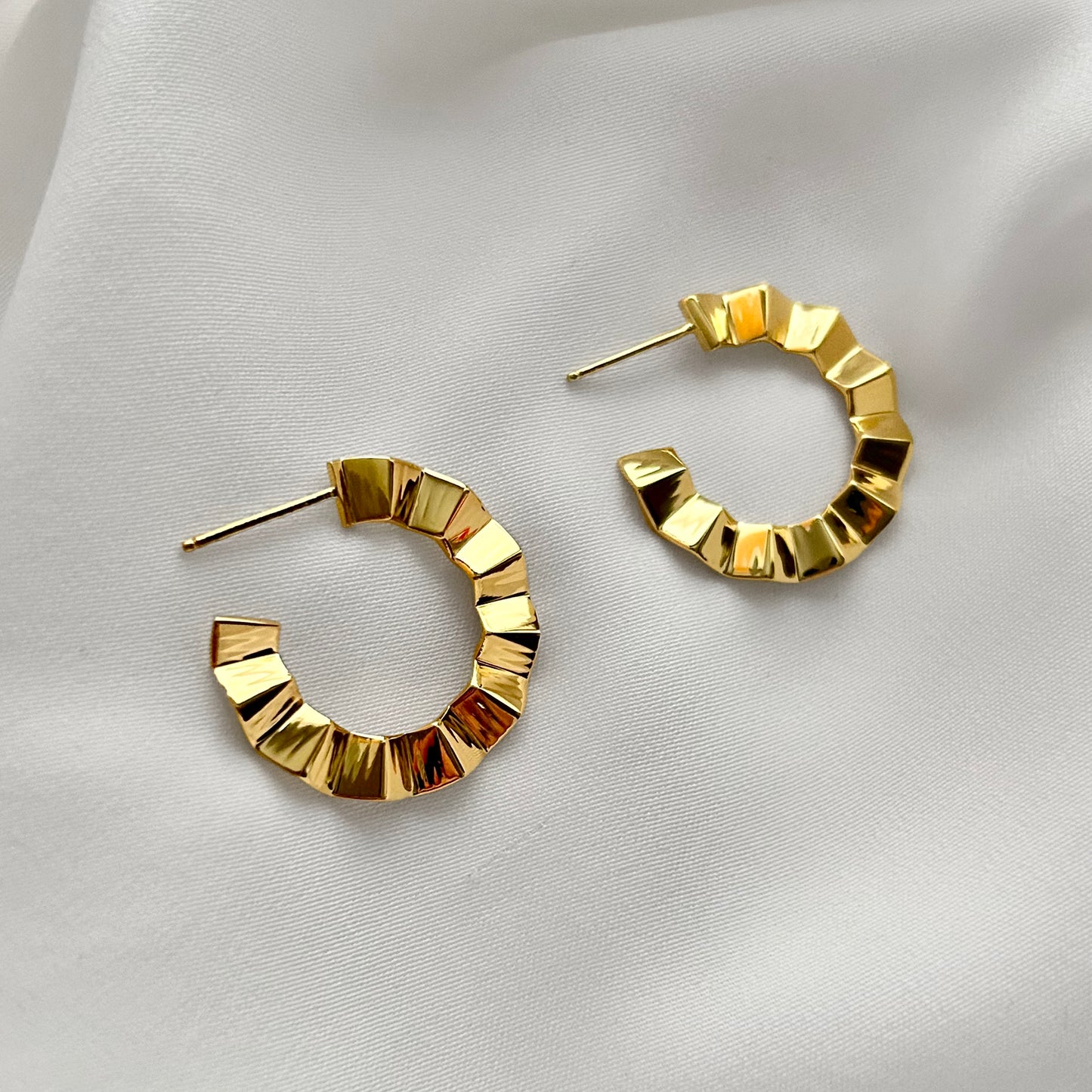 Gold hoop earrings on a light fabric background