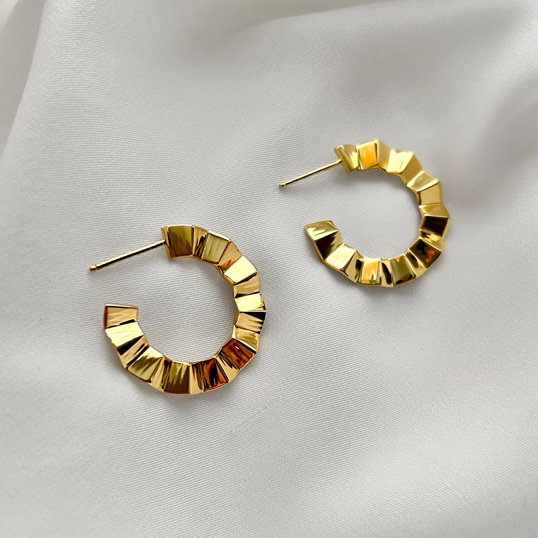 Gold hoop earrings on a light fabric background