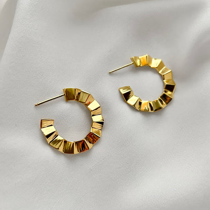 Gold hoop earrings on a light fabric background