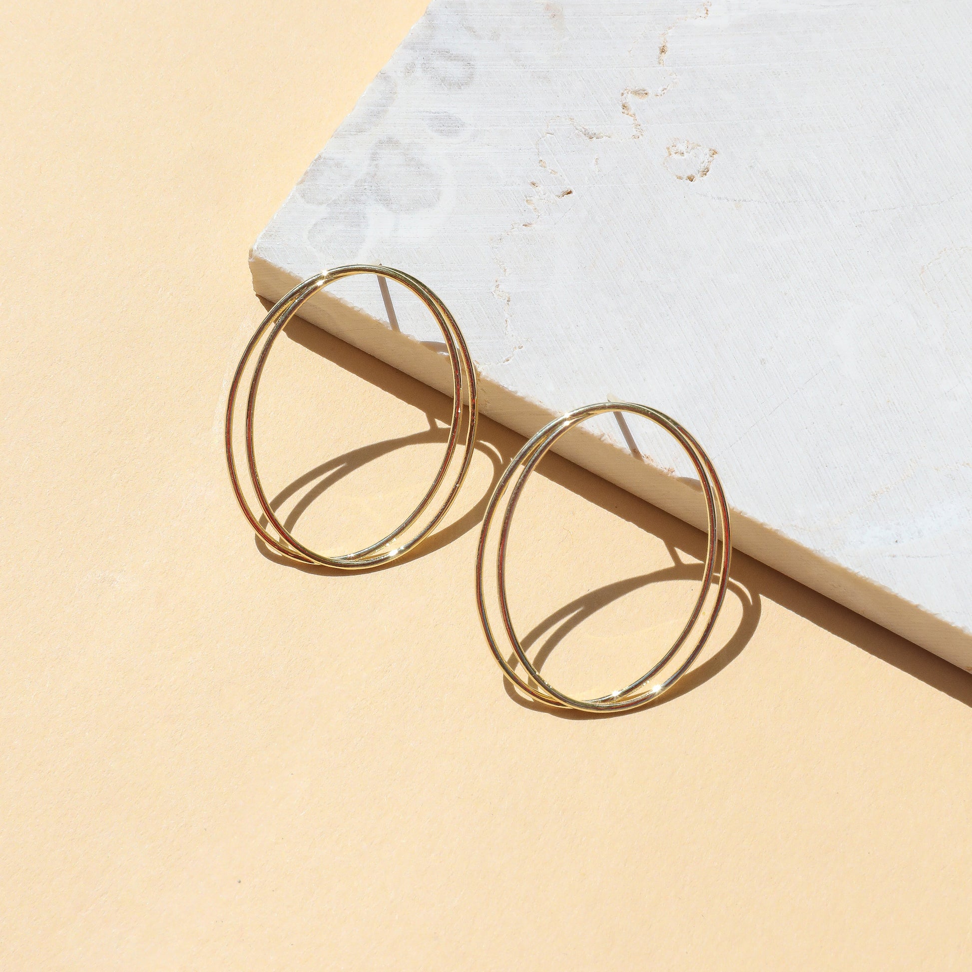 Gold hoop earrings on light background