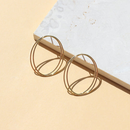 Gold hoop earrings on light background