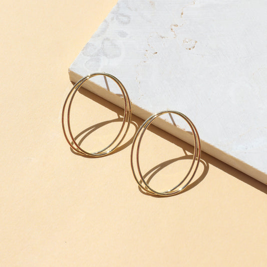 Gold hoop earrings on light background