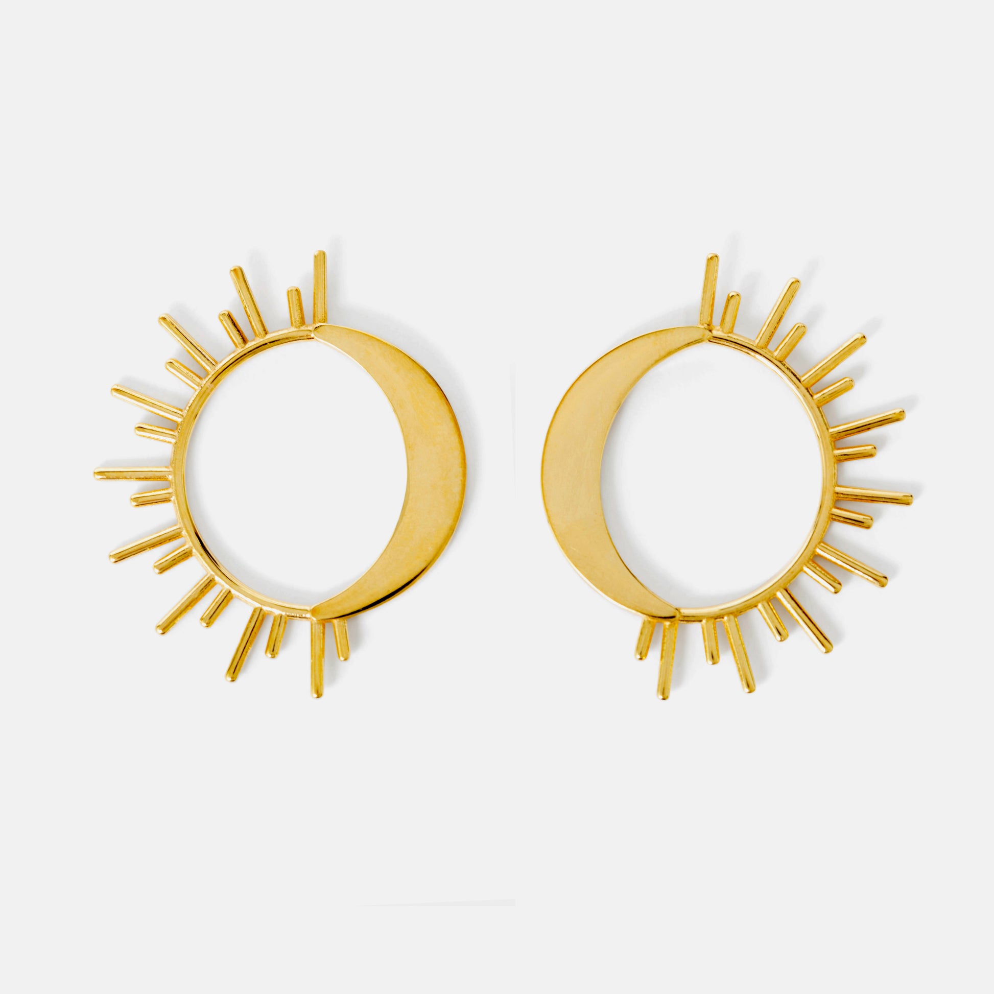 Pair of gold sun moon circular earrings on a white background