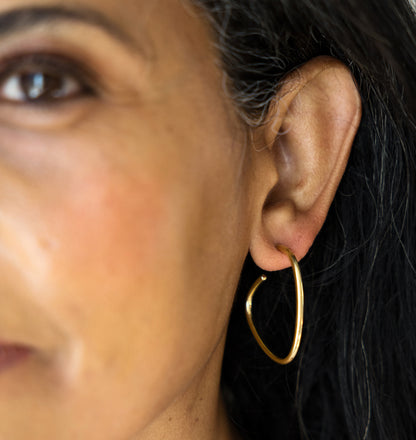 Close-up of a person wearing a gold hoop earring.