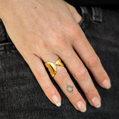 Hand wearing a gold ring with a black background