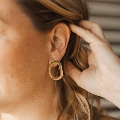 Gold geometric statement earring against a blurred background