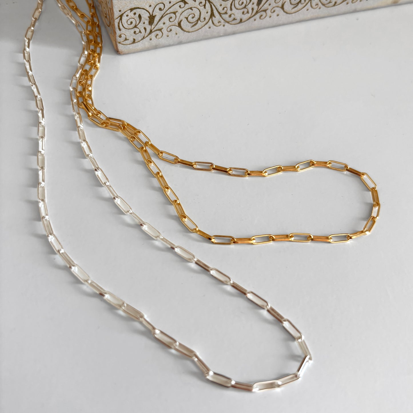 Gold and silver chain necklaces on a light gray surface