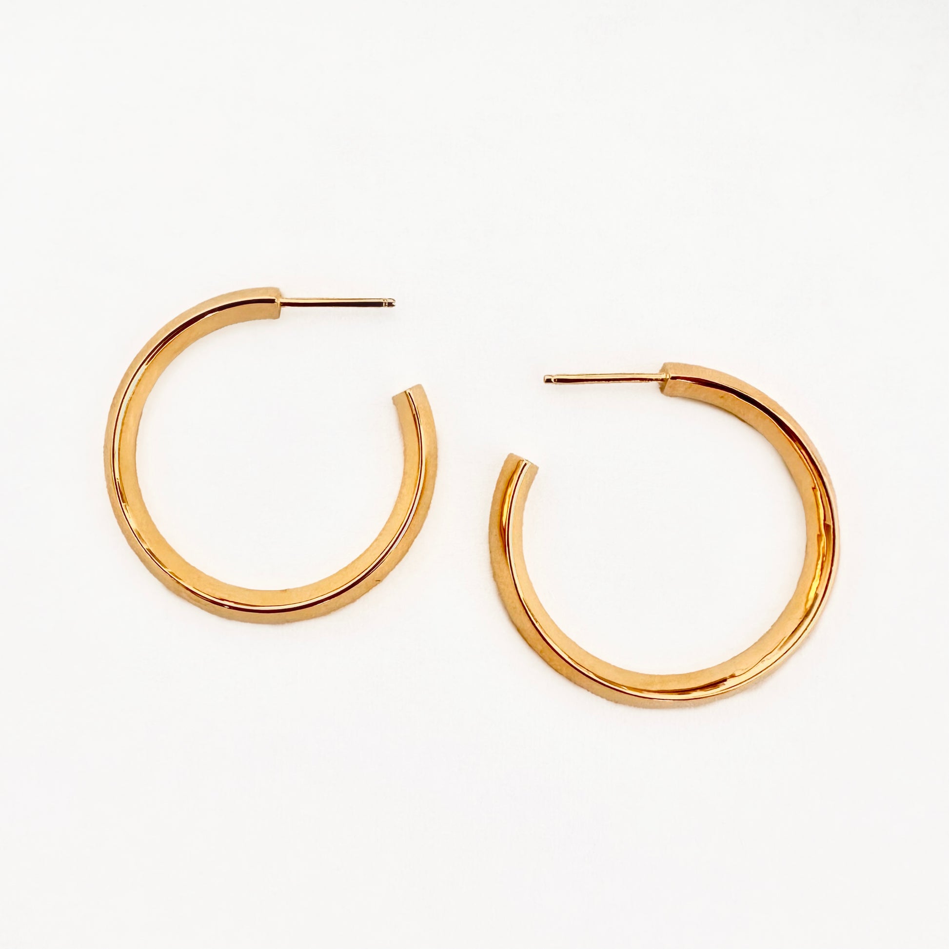 A pair of gold hoop earrings against a white background