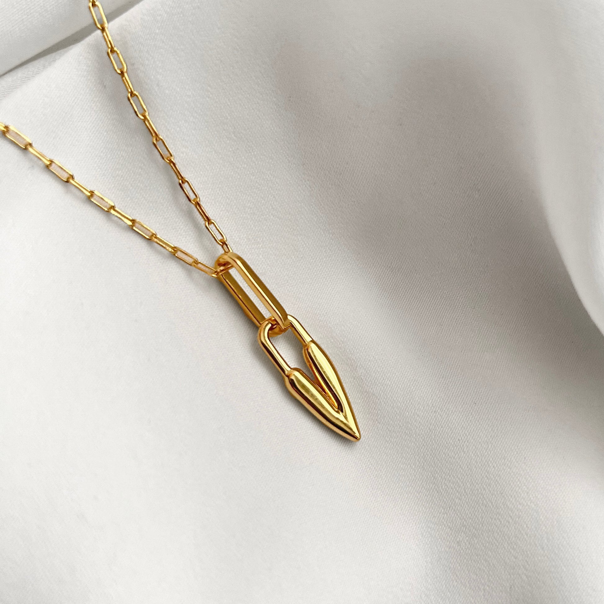 Gold necklace with a heart pendant on a white fabric background