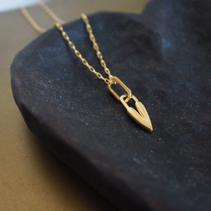 Gold necklace with a heart-shaped pendant on a dark surface